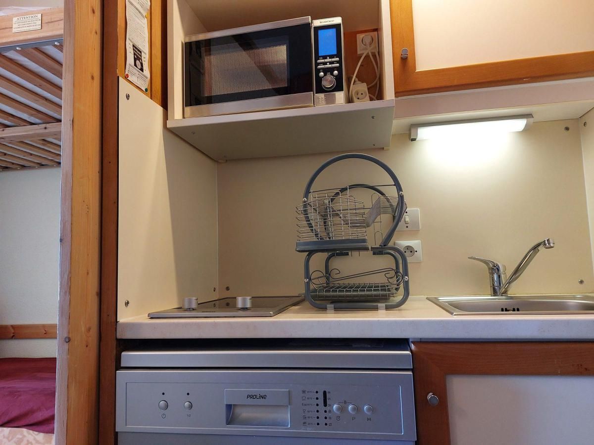 A compact kitchenette with a microwave, a small sink, and a dish rack.