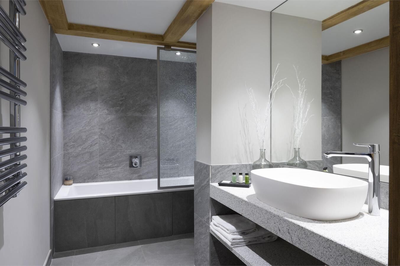 A modern bathroom with a large bathtub, a white sink, and a mirror.