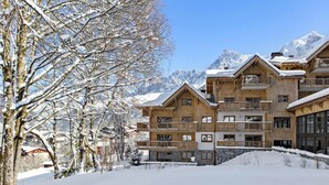 A multi-story wooden chalet with balconies, surrounded by snow-covered trees and mountains. - Wifi, fitness, swimming pool, sauna, hammam, balcony, tv, ski locker, 80m², Les Houches (Les Houches)
