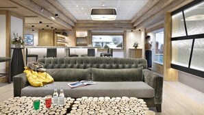 A modern living room with a grey sofa, a coffee table with wooden logs, and a kitchen in the background. - Wifi, fitness, swimming pool, sauna, hammam, balcony, tv, ski locker, 80m², Les Houches (Les Houches)