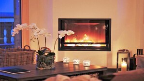 A cozy living room with a fireplace, a wicker basket, a vase with orchids, and a candle holder. - Chalet, 250m from ski slopes, balcony, fireplace or stove, parking, tv, 150m², Thyon (Hérémence)