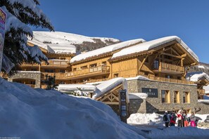A wooden chalet with stone walls, multiple balconies, and a sign indicating it is part of the RITEA hotel.