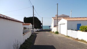 Un camino costero estrecho bordeado por edificios blancos con tejados rojos, que lleva al mar.
