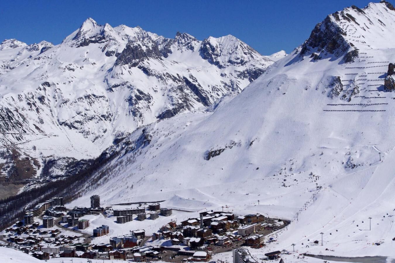 A snow-covered mountain town with buildings and ski slopes.