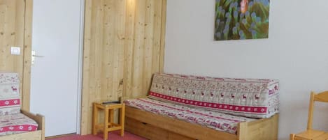 Una habitación de madera con un sofá, una mesita y una silla.