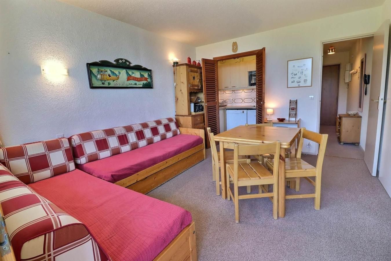 Ett mysigt vardagsrum med en soffa, ett matbord med stolar och ett kök i bakgrunden.
