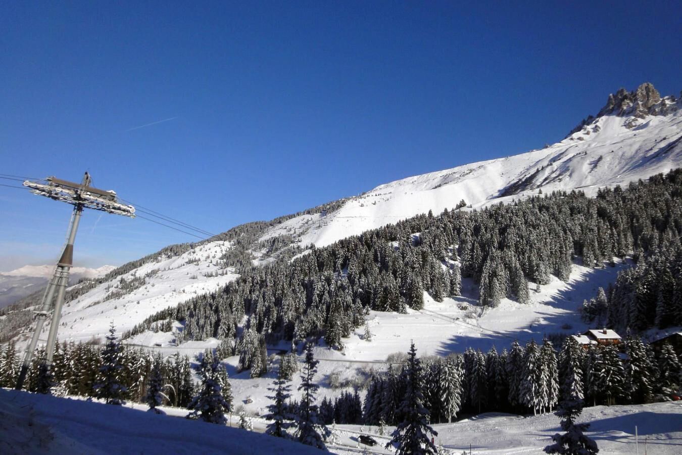 A snow-covered mountain with a ski lift and a cabin.