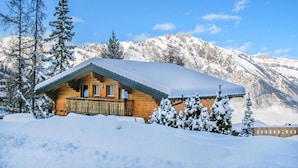 A wooden cabin with a balcony, surrounded by snow-covered trees and mountains. - Chalet, 350m from ski slopes, sauna, terrace, balcony, fireplace or stove, parking, tv, ski locker (La Tzoumaz)
