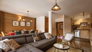 A modern living room with a sectional sofa, a dining area with a wooden table, and a kitchen with wooden cabinets. - 300m from ski lifts, fitness, sauna, hammam, balcony, fireplace or stove, ski locker, 85m², Valloire (Valloire)