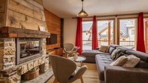 A cozy living room with a stone fireplace, a sofa, a chair, and a small table. - 300m from ski lifts, fitness, sauna, hammam, balcony, fireplace or stove, ski locker, 85m², Valloire (Valloire)