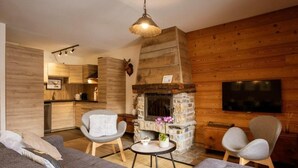 A cozy living room with a fireplace, a sofa, two armchairs, and a television. - 300m from ski lifts, fitness, sauna, hammam, balcony, fireplace or stove, ski locker, 85m², Valloire (Valloire)
