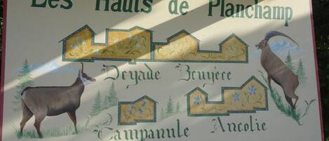 Un letrero con el texto 'Les Hauts de Planchamp' e ilustraciones de un ciervo y un carnero.
