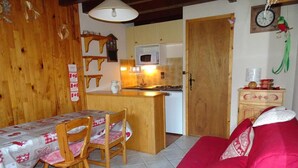 Una cocina acogedora con armarios de madera, un microondas y un comedor con mesa y sillas.