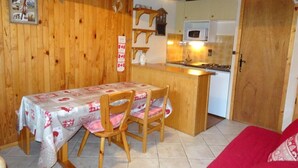 Una cocina acogedora con paredes de madera, una mesa de comedor con sillas y un sofá rojo.