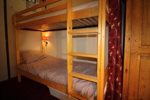 A bunk bed with a headboard, a wall-mounted lamp, and a radiator.