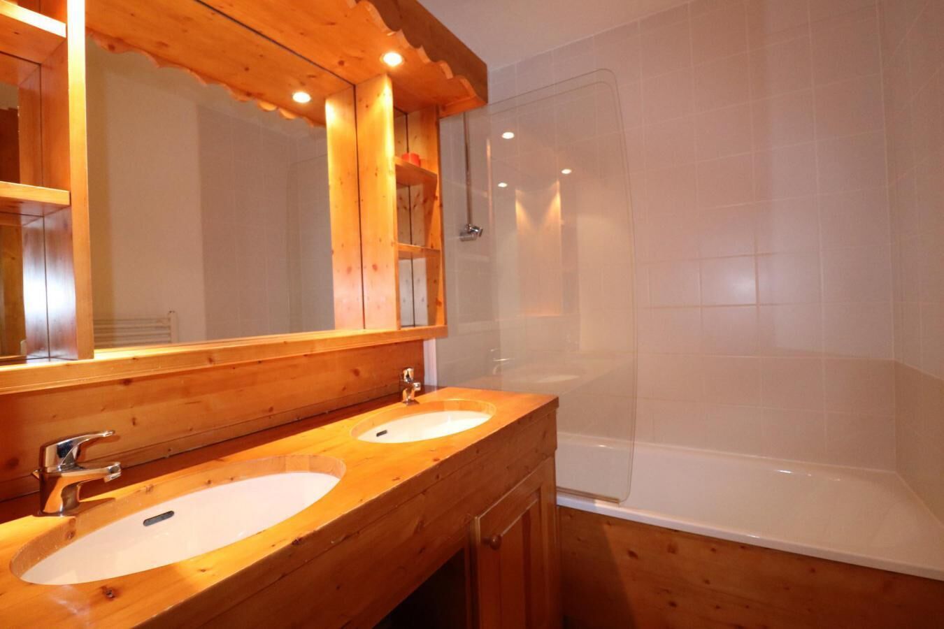 Une salle de bain en bois avec deux lavabos, un grand miroir et une baignoire.