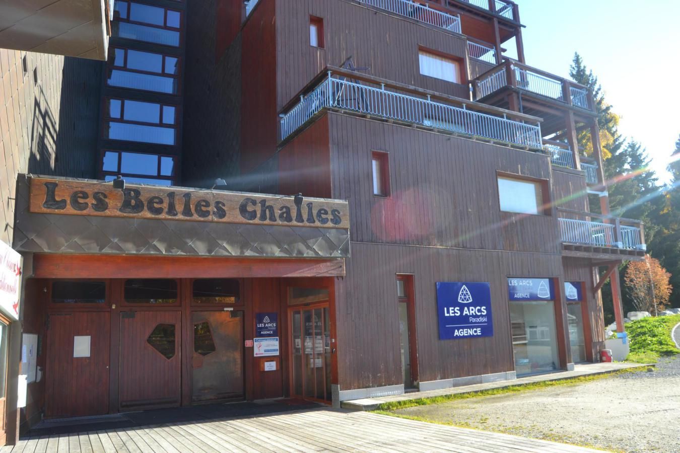 Ein Gebäude mit einem Schild, auf dem „Les Belles Challes“ steht, und einem weiteren Schild für „LES ARCS AGENCY“.