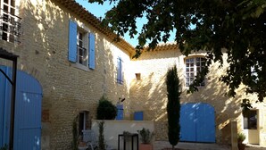 A courtyard with stone walls, blue doors, and potted plants.