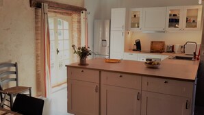 A kitchen with a central island, white cabinets, and a dining area with a table and chairs.