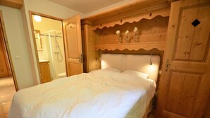 Une chambre à coucher avec une tête de lit en bois, un lit recouvert de draps blancs et des armoires en bois.