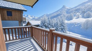 Un balcon en bois donnant sur un paysage enneigé, avec des montagnes en arrière-plan.