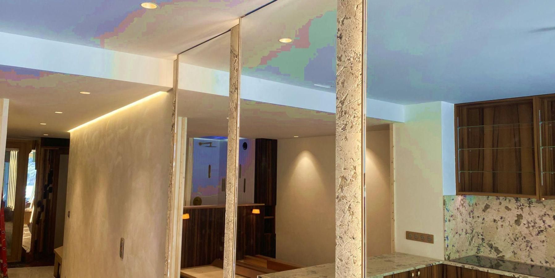 A modern interior with a high ceiling, a central column, and a view into another room.