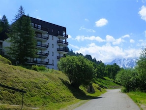 A multi-story building with balconies, surrounded by lush greenery and a mountain backdrop. - 170m from resort center, 4th floor, view mountain, balcony, tv, ski locker, 24m², Peisey-Vallandry (Peisey-Nancroix)