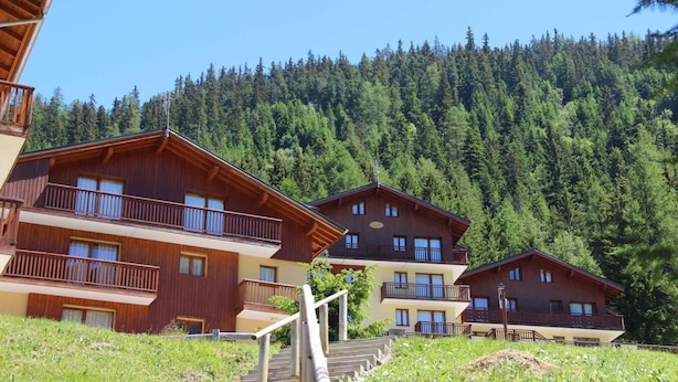 A row of wooden cabins with balconies, set against a forested hillside. - 300m from ski slopes, floor -1, view mountain, terrace, parking, tv, ski locker, 49m², Valfréjus (Valfréjus)