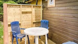 Una terraza de madera con dos sillas azules y una pequeña mesa.