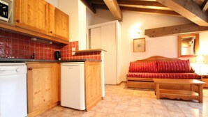 A compact kitchen with wooden cabinets, a white dishwasher, and a white refrigerator. - 10m from ski slopes, 4th floor, balcony, tv, ski locker, 33m², Val Cenis (Lanslevillard)