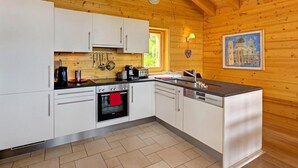 Una cocina con armarios blancos, estufa, pileta y un reloj en la pared.