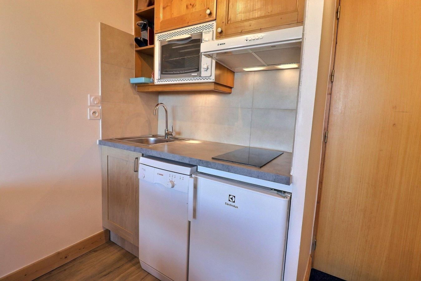 A compact kitchen with a Bosch dishwasher, a microwave, and a built-in oven.