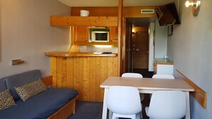 Interior compacto de una caravana con kitchenette, comedor y zona de estar.