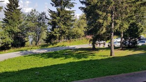 Un área de estacionamiento con coches, un sendero y árboles.