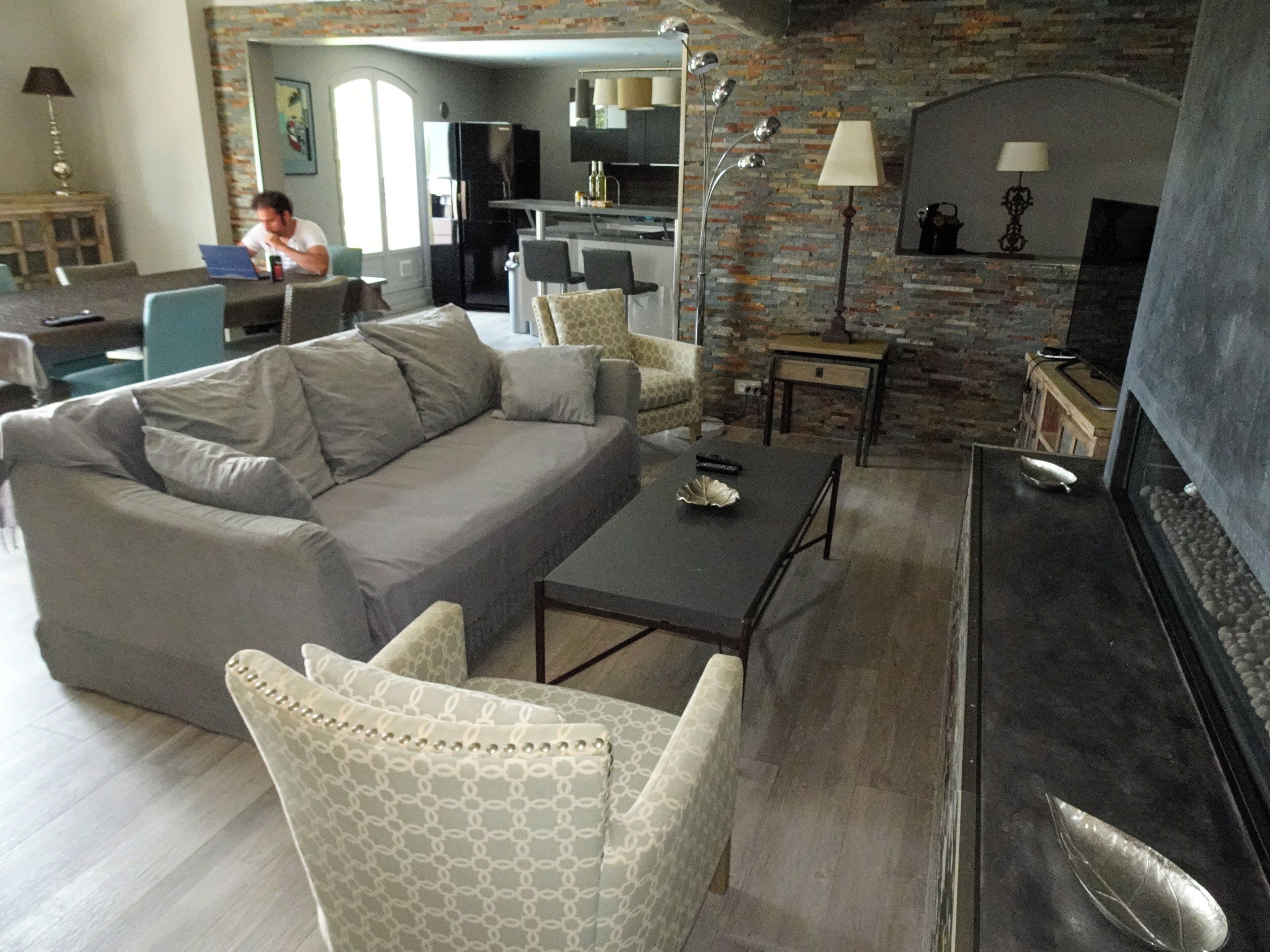 A modern living room with a grey sofa, patterned armchairs, a coffee table, and a fireplace.