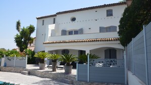 A two-story building with a tiled roof, a swimming pool, and potted plants. - Luxury Villa, Pool and Beautiful View (Saint-Raphaël)