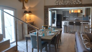 A dining area with a table set for six, a staircase, and a kitchen in the background. - Luxury Villa, Pool and Beautiful View (Saint-Raphaël)