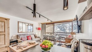 Eine moderne Küche mit Kochinsel, Essbereich und einem gemütlichen Wohnraum mit Sofa und Fernseher.