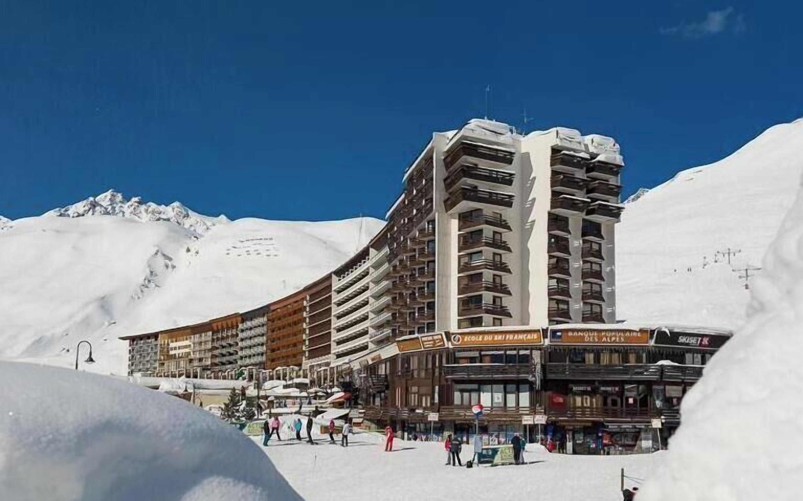 A hotel with multiple floors, ski lifts in the background, and a snowy mountain landscape.