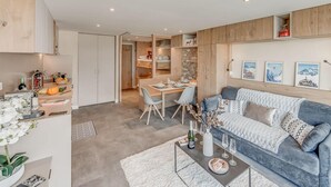 Ein modernes Wohnzimmer mit grauem Sofa, Essbereich und Küche.