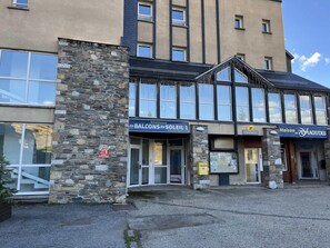 Um edifício com fachada de pedra, janelas amplas e placas com os dizeres 'Balcons du Soleil 1' e 'Maison de Peyragudes'.