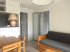 Um espaço compacto com uma mesa de jantar de madeira, um sofá e um abajur.