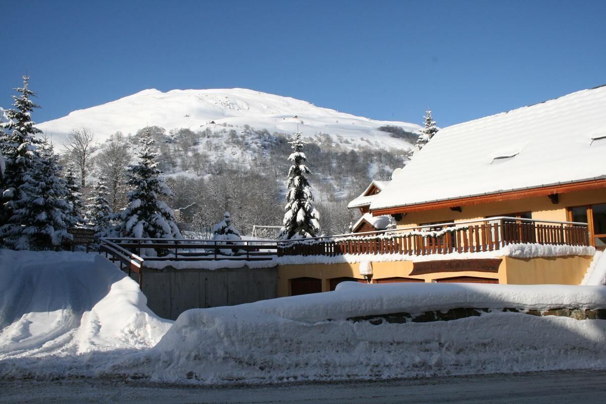 A snow-covered mountain with a building featuring a balcony and a snow-covered roof.