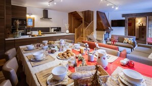 A modern living space with a dining area set for a meal, a kitchen, and a staircase leading to another level. - 300m from ski lifts, fitness, sauna, hammam, terrace, fireplace or stove, ski locker, 126m² (Valloire)