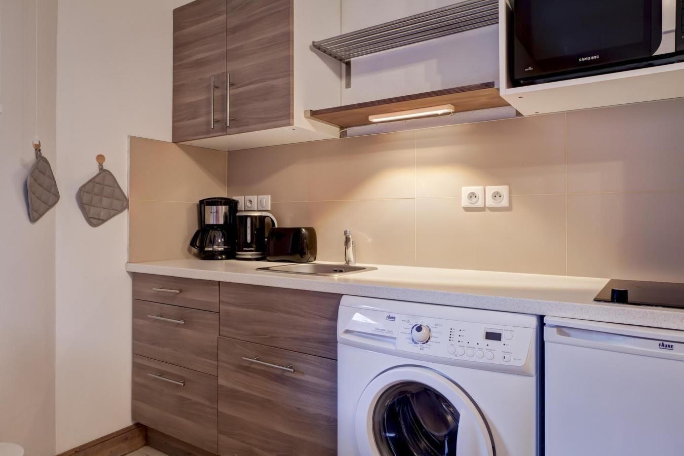 A compact kitchen with a built-in washer and dryer, a microwave, and a coffee maker.