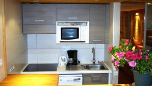 A compact kitchen with a built-in microwave, a coffee maker, and a sink.