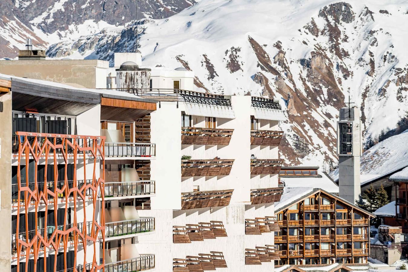 Hotel modern amb múltiples balcons, un remuntacamp i un paisatge de muntanya.
