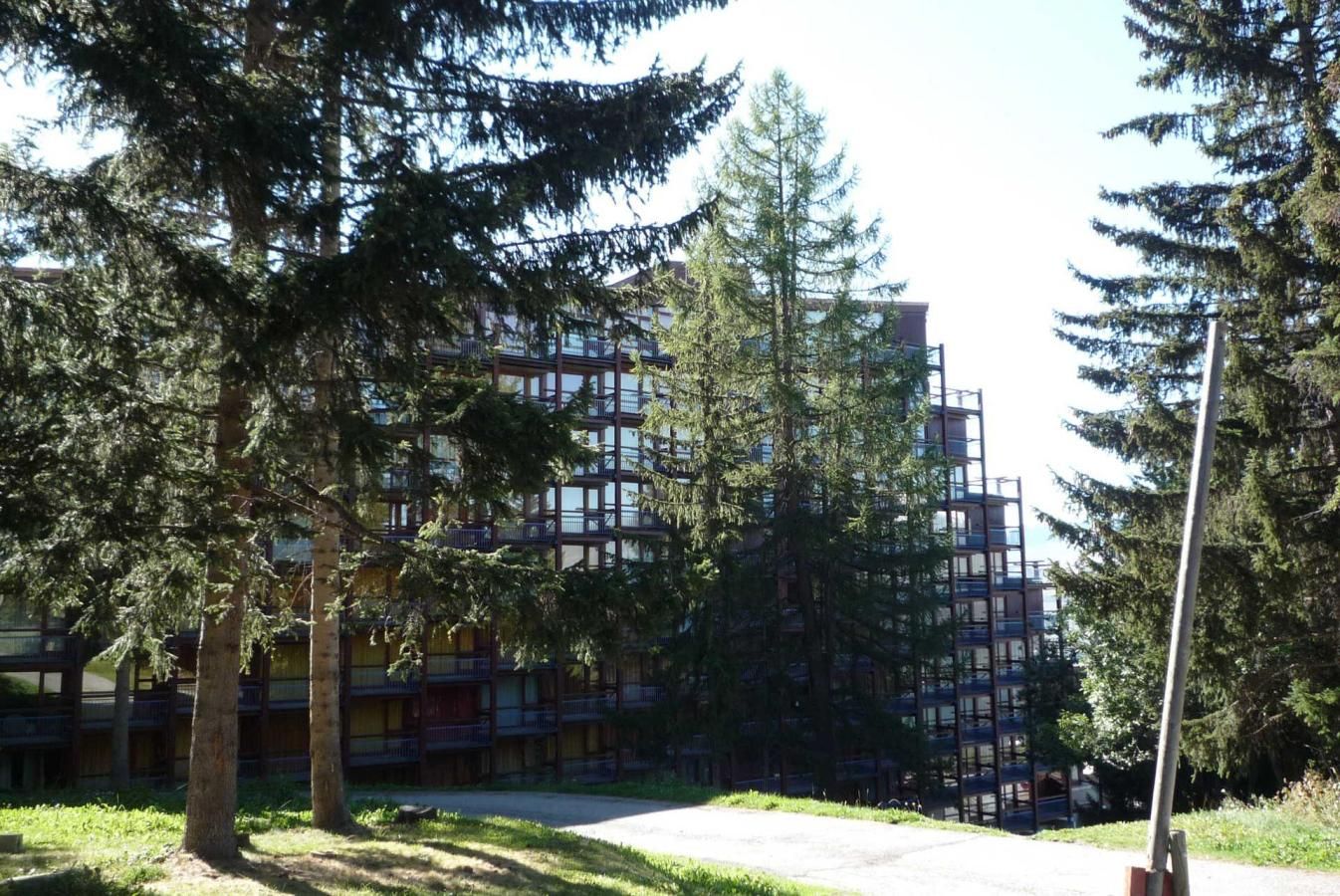 Un edifici de diverses plantes amb balcons, envoltat d'arbres.