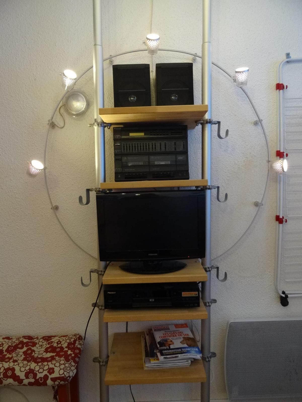 Een wandplank met elektronische apparaten en een televisietoestel.