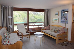 A cozy room with a sofa, a chair, a small table, and a view of a lake through large windows.